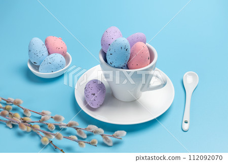Cup with colored Easter eggs on the blue background. Cup with colored Easter eggs on the blue background. 112092070