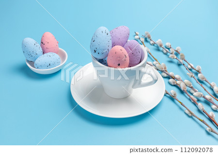 Cup with colored Easter eggs on the blue background. 112092078