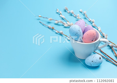 Cup with colored Easter eggs on the blue background. Cup with colored Easter eggs on the blue background. 112092081