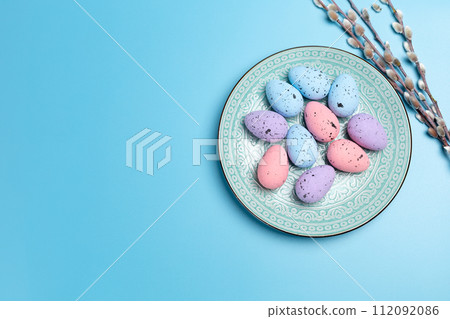 Plate with colored Easter eggs on the blue background. Plate with colored Easter eggs on the blue background. 112092086