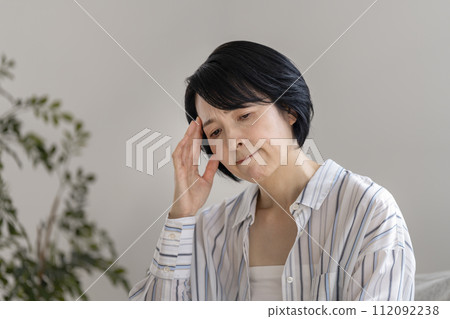 A woman in her early 50s holding her temples 112092238