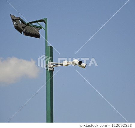 street lamp with CCTV cameras on a metal pole against blue sky 112092538