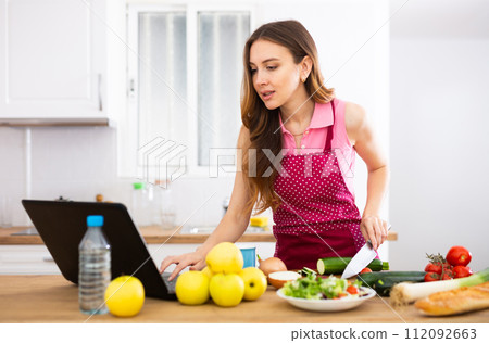 Woman cooking salad recipe from the Internet Woman cooking salad recipe from the Internet 112092663