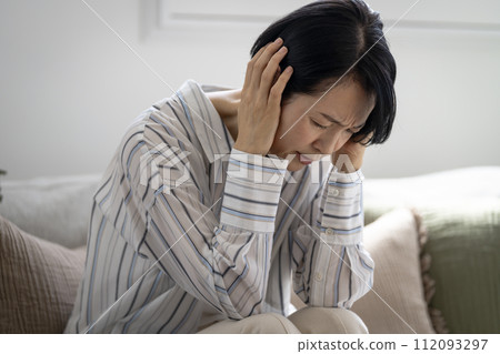 An early 50's woman holding her head 112093297
