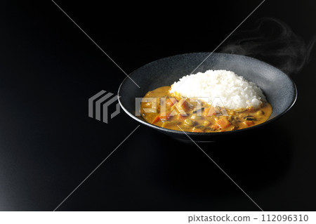 一張黑色背景下熱騰騰的咖哩飯和大量豬肉、南瓜和胡蘿蔔等蔬菜的照片。 一張黑色背景下熱騰騰的咖哩飯和大量豬肉、南瓜和胡蘿蔔等蔬菜的照片。 112096310