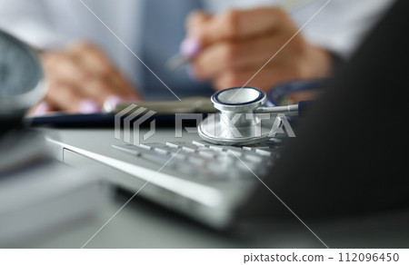 Stethoscope head lying on laptop computer keyboard 112096450