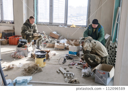 Workers in work clothes prepare tools and materials 112096589