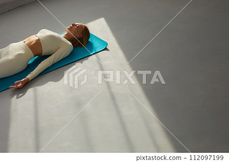 Young woman practicing corpse asana in yoga studio. Savasana pose. Young woman practicing corpse asana in yoga studio. Savasana pose. 112097199