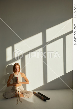 Woman practicing yoga and meditation in lotus pose on yoga mat, relaxed. Mindful meditation concept. Wellbeing Woman practicing yoga and meditation in lotus pose on yoga mat, relaxed. Mindful meditation concept. Wellbeing 112097235