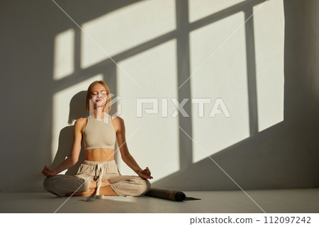 Woman practicing yoga and meditation in lotus pose on yoga mat, relaxed. Mindful meditation concept. Wellbeing Woman practicing yoga and meditation in lotus pose on yoga mat, relaxed. Mindful meditation concept. Wellbeing 112097242