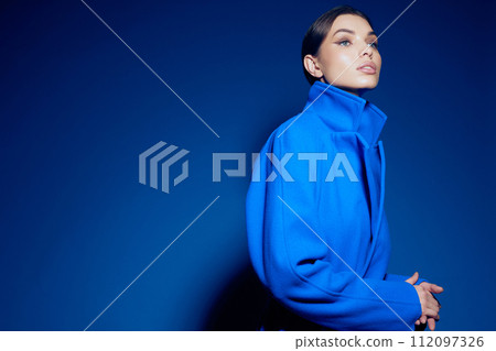 fashion portrait of young elegant woman in blue coat on blue background fashion portrait of young elegant woman in blue coat on blue background 112097326
