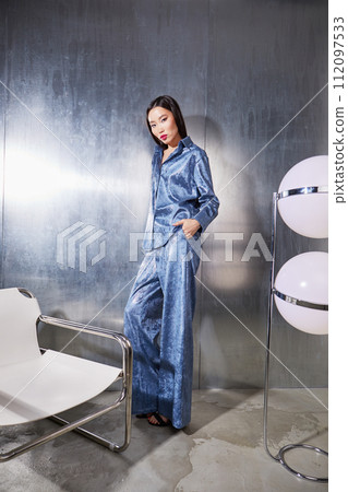 Fashion asian female model in blue glitter suit posing on metallic modern futuristic location. 112097533