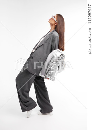 Fashion asian female model in silver down jacket and grey suit. Fashion asian female model in silver down jacket and grey suit. 112097627