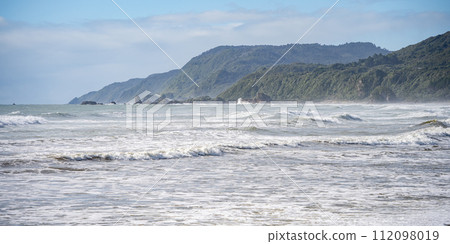 Rough exotic coastal landscape with big waves and rainforest vegetation on a sunny day, New Zealand 112098019