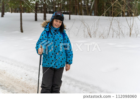 Happy caucasian boy wearing warm clothes and hat walking on snowy winter road Happy caucasian boy wearing warm clothes and hat walking on snowy winter road 112098060
