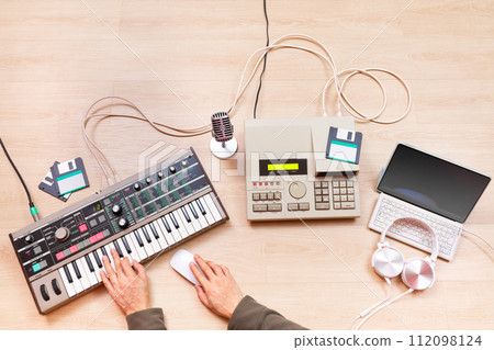 top view of male music producer, composer, arranger hands arranging a hit song on synthesizer keyboard, sequencer, laptop computer. music production or recording concept 112098124