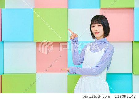 Colorful background with young woman in pointing pose Colorful background with young woman in pointing pose 112098148