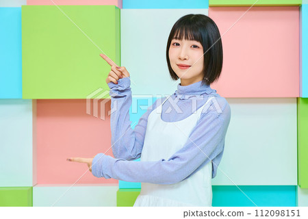 色彩繽紛的背景與年輕女子的指點姿勢 色彩繽紛的背景與年輕女子的指點姿勢 112098151