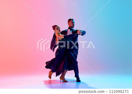 Beautiful young man and handsome woman, ballroom dancers making performance, dancing against gradient pink blue background in neon light Beautiful young man and handsome woman, ballroom dancers making performance, dancing against gradient pink blue background in neon light 112098271