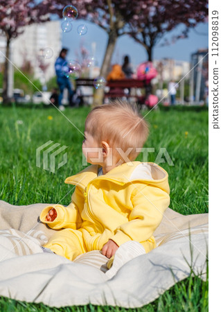 Adorable one-year-old boy in yellow overalls enjoying the outdoors 112098819