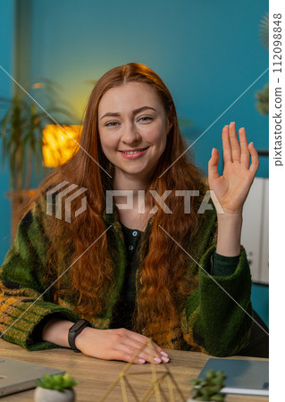 Woman smiling friendly at camera waving hands gesturing hello hi greetings online video call at home Woman smiling friendly at camera waving hands gesturing hello hi greetings online video call at home 112098848