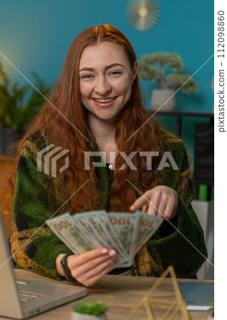 Business woman counting money cash and using laptop calculates dividends profits finances at office Business woman counting money cash and using laptop calculates dividends profits finances at office 112098860