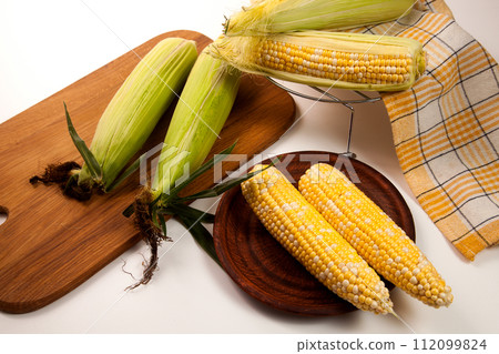 Clay plate with several cobs sweet corn on white wooden background.. Clay plate with several cobs sweet corn on white wooden background.. 112099824
