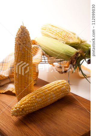 Cutting board with two cobs sweet corn on white wooden background.. Cutting board with two cobs sweet corn on white wooden background.. 112099830