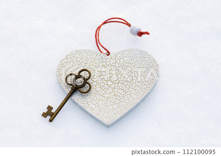 Heart-shaped toy and key on the snow, top view Heart-shaped toy and key on the snow, top view 112100095