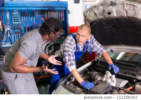 Two car mechanic diagnosing auto engine problem in service 112100302