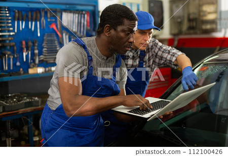 Two masters are replacing the filter in car on workplace 112100426