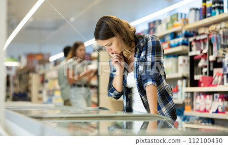 Young woman choosing frozen food in supermarket 112100450
