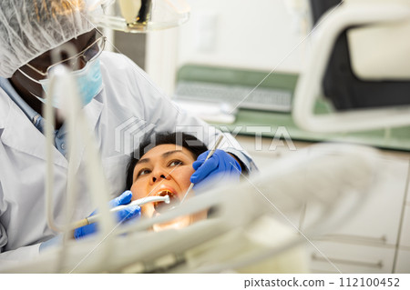 Closeup view of dentist treating teeth of woman in dentist office 112100452