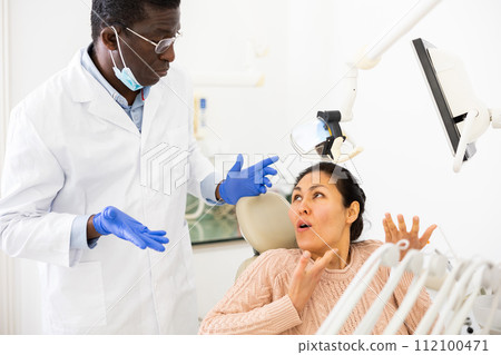Dissatisfied woman talking to confused dentist after dental treatment 112100471