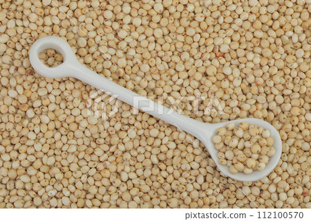 background of sorghum seeds with ceramic spoon. Top view. Flat lay. 112100570
