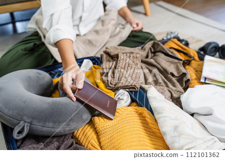 Young woman check baggage lists on notebook to prepare for traveling trip Young woman check baggage lists on notebook to prepare for traveling trip 112101362
