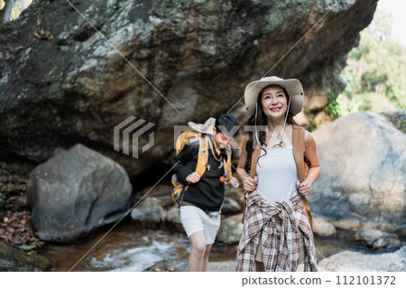 Happy LGBT Lesbian couple Travelers Hiking with Backpacks in waterfall Trail. LGBT Lesbian Couple Hikers with backpacks walks in mountains in vacation Happy LGBT Lesbian couple Travelers Hiking with Backpacks in waterfall Trail. LGBT Lesbian Couple Hikers with backpacks walks in mountains in vacation 112101372