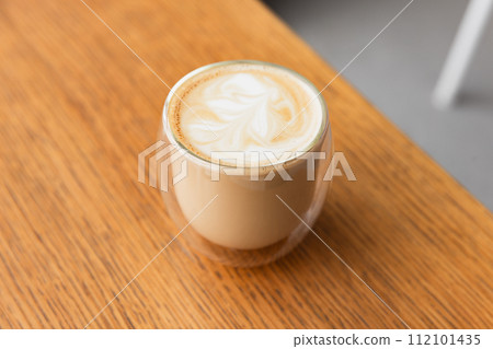 Glass of cappuccino coffee stands on wooden table, close-up photo 112101435