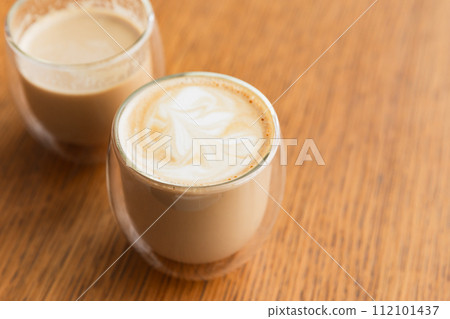 Two glasses of cappuccino coffee stand on wooden table, close-up Two glasses of cappuccino coffee stand on wooden table, close-up 112101437