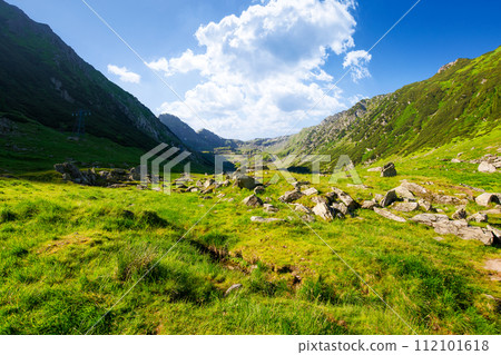 valley of carpathian mountains in morning light. stones on the grassy meadow. fagaras range of romania. beautiful landscape on a sunny summer day 112101618