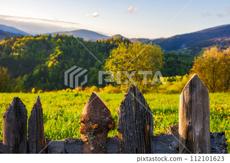 weathered wooden fence. mountainous rural landscape of transcarpathia, ukraine in spring blurred in the distance. carpathian countryside with forested rolling hill beneath a blue sky with white fluffy weathered wooden fence. mountainous rural landscape of transcarpathia, ukraine in spring blurred in the distance. carpathian countryside with forested rolling hill beneath a blue sky with white fluffy 112101623