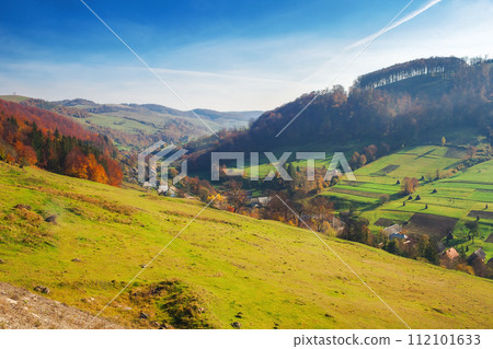 rural landscape of carpathian mountains. beautiful countryside scenery in autumn season with fields on the hills and village in the valley 112101633
