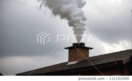 Dense smoke comes out of the chimney of a private house due to the burning of wood Dense smoke comes out of the chimney of a private house due to the burning of wood 112102089
