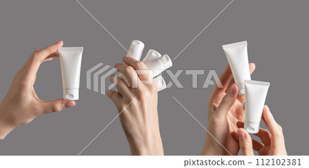 Hand holding cream tubes, cosmetic products mockups isolated on white 112102381