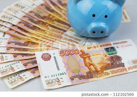 Piggy bank and Russian banknotes on a gray background. The concept of accumulation and storage of money 112102560