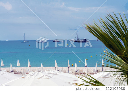 Amazing view on private beach with tents and white sand and boats free anchored in Cannes bay Amazing view on private beach with tents and white sand and boats free anchored in Cannes bay 112102988
