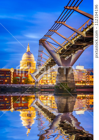 London, England - UK. St Paul's Anglican cathedral dome and Millennium Bridge, early in the evening twilight Thames River water reflection, United Kingdom. London, England - UK. St Paul's Anglican cathedral dome and Millennium Bridge, early in the evening twilight Thames River water reflection, United Kingdom. 112104196