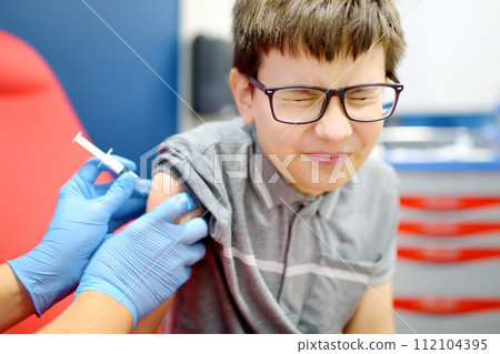 A little boy is being vaccinated. A child is very afraid of the injection. Schoolkid nervous during scheduled vaccination. Close up A little boy is being vaccinated. A child is very afraid of the injection. Schoolkid nervous during scheduled vaccination. Close up 112104395