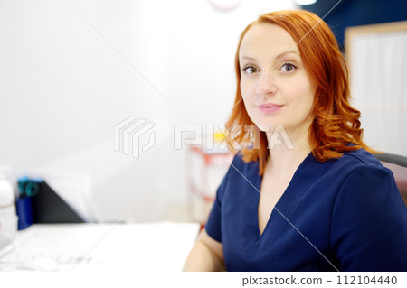 Portrait of a smiling female neurologist looking at camera in the office of a modern clinic. The neurology doctor is at work. 112104440