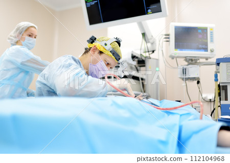 Surgeons are during maxillofacial operation in modern hospital. Teamwork of doctors. Maxillofacial surgery. Surgeons are during maxillofacial operation in modern hospital. Teamwork of doctors. Maxillofacial surgery. 112104968
